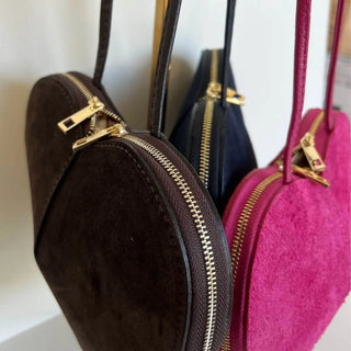 
                    
                      Detailaufnahme des Logos auf der Herzl Tasche Velourleder dunkelblau, pinkes Innenfutter, Damenhandtasche
                    
                  
