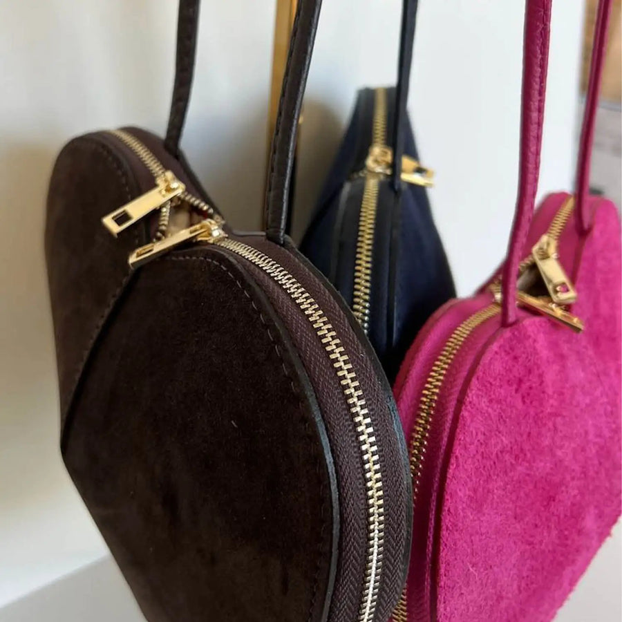Detailaufnahme des Logos auf der Herzl Tasche Velourleder dunkelblau, pinkes Innenfutter, Damenhandtasche